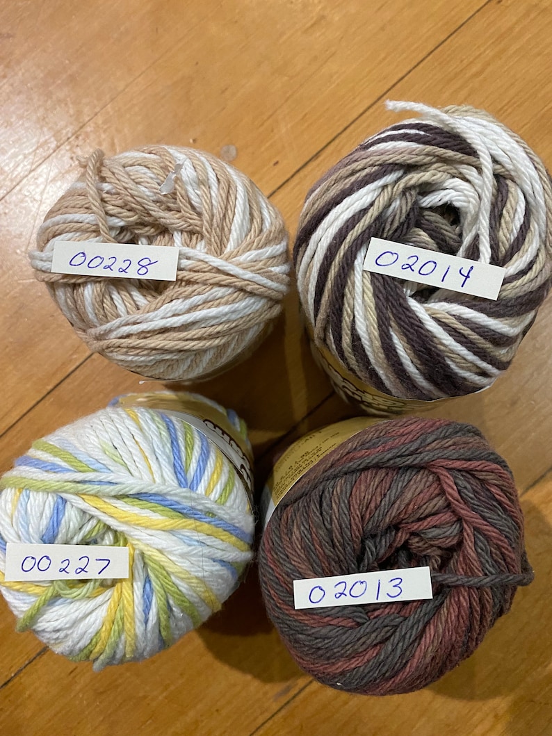May include: Four balls of yarn in different color combinations. The yarn is striped with white, brown, blue, yellow, and red. The yarn balls are labeled with numbers: 00228, 02014, 00227, and 02013.
