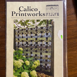 May include: A quilt pattern titled "In The City" from Calico Printworks. The pattern features a black, white and green patchwork design with a border of green leaves and white flowers.