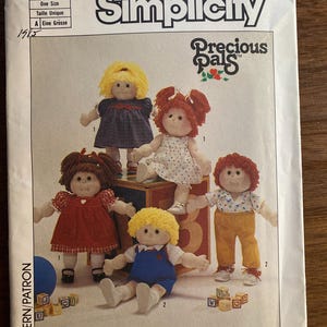 May include: Simplicity sewing pattern featuring Precious Pals dolls. The pattern cover displays several fabric dolls with yarn hair, wearing various outfits. The pattern number is 6999, and the copyright is 1984.