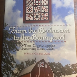 May include: Book cover featuring a red barn with a white star quilt block on the side. The title of the book is "From the Bedroom to the Barnyard: A Nine-Block Sampler Honoring Barn Quilts" by Kansas City Star Quilts.