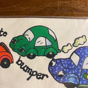 May include: A green car with a white bumper and black wheels is bumping into a blue car with white polka dots. The blue car has a white cloud behind it. The text "bumper" is written in black below the green car.