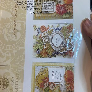 Może przedstawiać: Pakiet warstwowych wykrojnik&oacute;w do liści autorstwa Anny Griffin. Opakowanie zawiera trzy dekoracyjne projekty kart z elementami o tematyce jesiennej, w tym dynie, liście i akcenty kwiatowe. Karty zawierają słowa "grateful" i "thanks for your love & support."