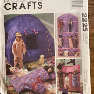 May include: A McCall's Crafts 2225 sewing pattern envelope featuring illustrations of doll-sized accessories including a purple tent, a floral sleeping bag, a hanging wall organizer with clear pockets, and a pink fabric tote bag for dolls.
