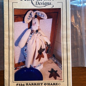 May include: A sewing pattern for a 16-inch bag holder and placemats featuring a cute bunny with blue and white gingham fabric. The pattern is titled "#234 HARRIET O'HARE®".