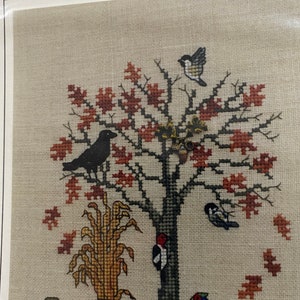May include: Cross stitch pattern depicting an autumn scene with a tree, birds, and a squirrel. The text "Autumn Feeder... No. 40" is visible in the top left corner.