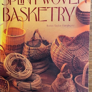 May include: A book titled "Splint Woven Basketry" by Robin Taylor Daugherty, showcasing a range of woven baskets in various shapes and sizes. The baskets are crafted from natural materials and have a rustic, handmade appearance.