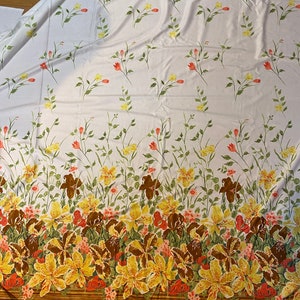 May include: White fabric with a floral pattern. The fabric features a repeating pattern of small red, yellow, and green flowers. The bottom of the fabric has a border of larger yellow, red, and brown flowers.