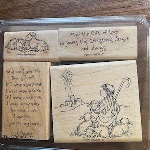 May include: A collection of wooden stamps featuring festive imagery and text. The stamps depict sheep, a shepherd with sheep, and the message "May the Gift of Love be yours this Christmas Season and always."