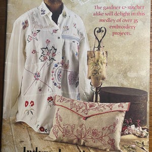 Peut inclure: Une couverture de livre intitulée "A Vintage Bouquet" avec une chemise blanche brodée de fleurs, un petit sac brodé et un coussin beige avec une broderie florale rouge. Le texte indique "The gardner & stitcher alike will delight in this medley of over 35 embroidery projects."