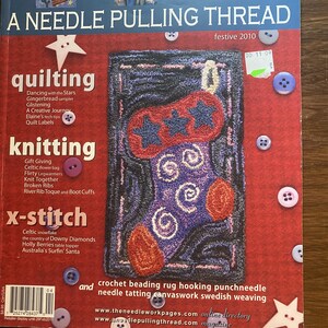 May include: A magazine titled A Needle Pulling Thread, festive 2010 edition. The red cover features a central image of a rug-hooked Christmas stocking with blue stars and purple swirls, surrounded by scattered white and purple buttons and star shapes.