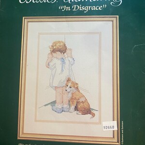 Könnte beinhalten: Gerahmtes Kreuzstich-Kunstwerk "In Disgrace" von Bessie Pease Gutmann, das ein Kind und einen Hund zeigt. Das Design ist mattiert und in einem 35,56 cm x 45,72 cm großen Rahmen gerahmt.