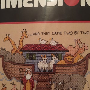 Op de afbeelding: Een kruissteekpatroon met een kleurrijke illustratie van Noachs Ark met dieren, waaronder giraffen, olifanten, leeuwen en een kameel. De tekst "...AND THEY CAME TWO BY TWO" is in de afbeelding opgenomen.