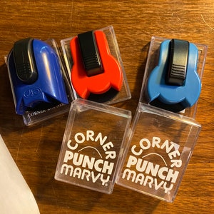 Könnte beinhalten: Drei Ecklocher in blauen, roten und blauen Plastikboxen. Die Boxen sind mit "Corner Punch Marvy" beschriftet.