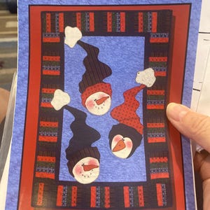 May include: A printed paper featuring a design of snowmen and penguins. The design includes three snowmen with black hats and red scarves, and a penguin with a carrot nose. The text "Snowmen & Penguins" is at the bottom, with "Whistlepig Creek Productions" at the top.