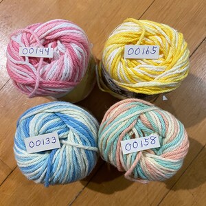 May include: Four balls of yarn in different color combinations: pink and white, yellow and white, blue and white, and peach and white. Each ball has a handwritten number tag attached.