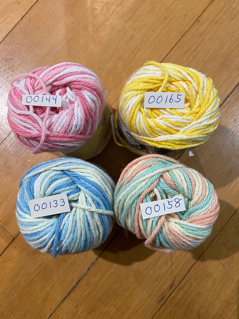 May include: Four balls of yarn in different color combinations: pink and white, yellow and white, blue and white, and peach and white. Each ball has a handwritten number tag attached.