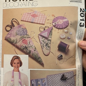 May include: A sewing pattern for a variety of home decor projects, including a pincushion, a scissor holder, and a needle case. The pattern is by Nancy Zieman and is part of McCall's Home Decorating line.