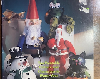 May include: The cover of a book, "Let's Paint Pot Bellies", displays painted figurines: a gnome, a turtle, Santa Claus, a snowman, and a black cat in a pumpkin. The book promises easy painting of critters and characters to warm your heart.