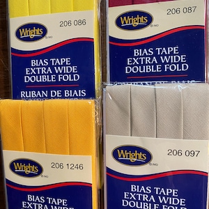 Pode incluir: Quatro pacotes de fita de viés em amarelo, vermelho, bege e amarelo. Cada pacote tem a marca Wrights e o texto "Bias Tape Extra Wide Double Fold" e "Ruban de biais double extra largeur". Os números dos pacotes são 206 086, 206 087, 206 097 e 206 1246.