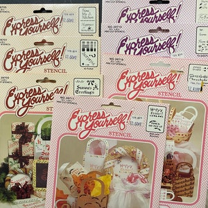 May include: A set of 6 pre-cut stencils for crafting and decorating. The stencils feature various designs, including "Express Yourself!" with a whimsical font, "Happy Easter!" with a basket and bunny, and "Season's Greetings" with a bow and ribbon. The stencils are packaged on pink and white cards with the product name and number.
