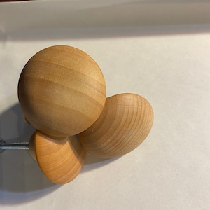 Może przedstawiać: Trzy drewniane gałki w jasnobrązowym kolorze. Gałki są okrągłe i mają gładkie, polerowane wykończenie.