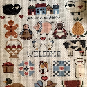 Pode incluir: Um padrão de ponto cruz intitulado Country Caboodle Mini Series #1 por Anne Van Wagner Young. O design apresenta vários motivos, incluindo uma ovelha preta, casas, um porco, uma vaca, uma jarra de leite, uma melancia, patos e o texto glad we're neighbors e WELCOME.