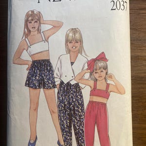 May include: A vintage sewing pattern labelled "NEW LOOK 2037" showing illustrations of three young women in matching outfits. The outfits include a white crop top and shorts, a white jacket and patterned trousers, and a pink crop top and trousers.
