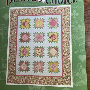 Puede incluir: Un patrón de edredón titulado "Dealer's Choice" con un borde floral y un diseño central de nueve bloques cuadrados. Cada bloque presenta una tela estampada diferente en tonos de rosa, amarillo y rojo. El precio es de 16,60 €.