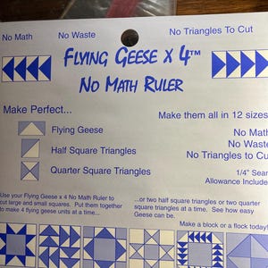 May include: A white and blue quilting ruler with the text "Flying Geese x 4" and "No Math Ruler". The ruler includes instructions for making Flying Geese, Half Square Triangles, and Quarter Square Triangles. The ruler is designed to cut large and small squares.
