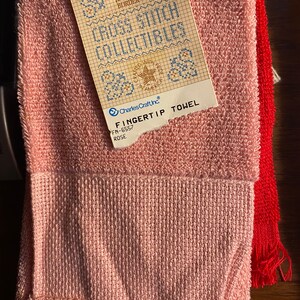 May include: A pink fingertip towel with a white label that says "Cross Stitch Collectibles" and "Charles Craft, Inc."  The label also says "Fingertip Towel" and "FN-6557 ROSE".