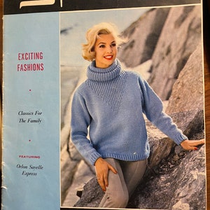 May include: A vintage magazine cover for "Spinnerin" showing a woman in a light blue turtleneck sweater. The cover includes the text "Exciting Fashions" and "Classics For The Family". The magazine is Volume 156.