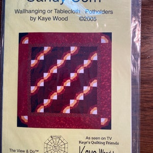 May include: A yellow and brown paper pattern for a quilt called "Candy Corn" by Kaye Wood. The pattern is for a wallhanging or tablecloth potholders. The pattern includes a diagram of an octagon shape and the text "View & DoTM Series" and "©2005".