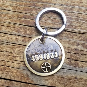May include: A brass key chain with a round tag featuring the number 4591834 and a cross symbol.