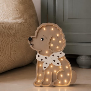 May include: A light brown, dog-shaped lamp with a matte finish. The lamp features a white scarf with small brown heart patterns around the neck. Multiple small, warm-toned LED lights are embedded throughout the body, illuminating the silhouette.
