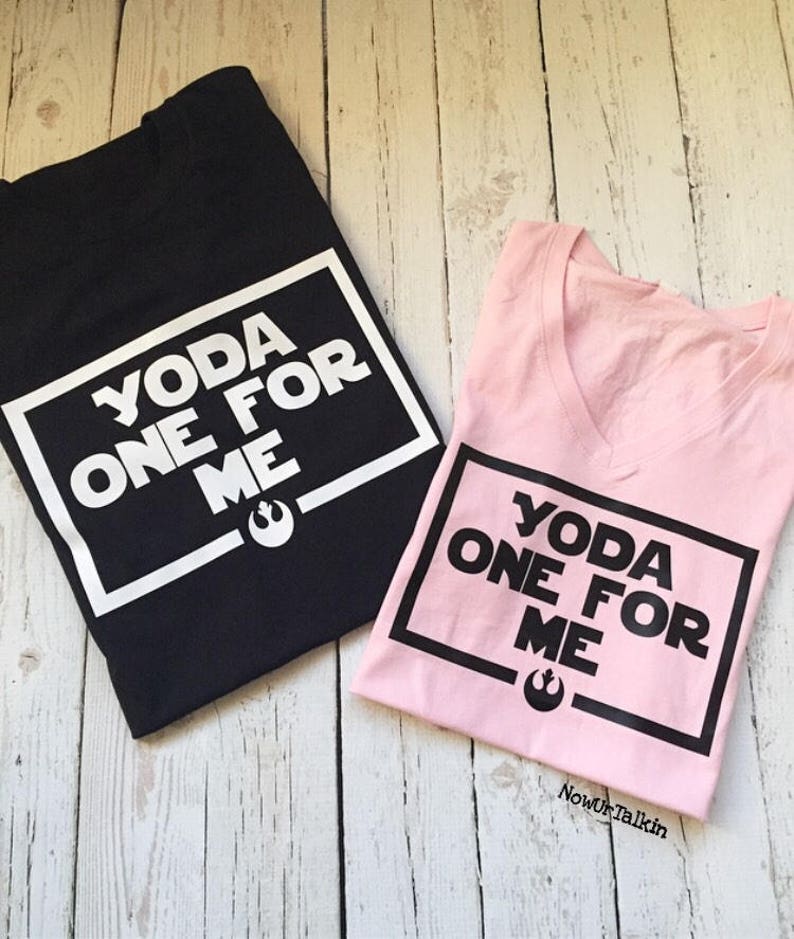 K&ouml;nnte beinhalten: Zwei T-Shirts mit einem schwarz-wei&szlig;en Grafikdesign. Das schwarze T-Shirt hat den Text "YODA ONE FOR ME" in einem wei&szlig;en Kasten. Das rosa T-Shirt hat den gleichen Text in einem schwarzen Kasten.