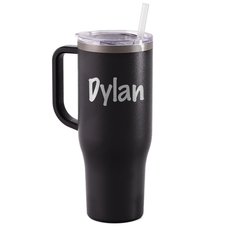 K&ouml;nnte beinhalten: Schwarzer isolierter Becher mit Henkel, transparentem Deckel und Strohhalm. Der Name "Dylan" ist in wei&szlig;er Schrift aufgedruckt. Der Becher h&auml;lt Getr&auml;nke kalt oder hei&szlig;.