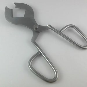 May include: A silver metal tool with two handles and a sharp blade. The tool is used for cutting and trimming.