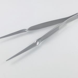 May include: A pair of silver-coloured tweezers with a slightly curved tip. The tweezers are made of metal and have a textured grip.