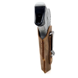 May include: A brown leather holster with a metal clip for a Ruger pistol.