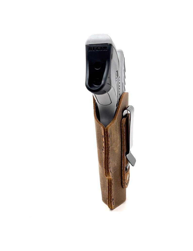 May include: A brown leather holster with a metal clip for a Ruger pistol.