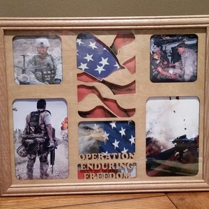 May include: A wooden picture frame with a cutout of an American flag. The frame has five photos of soldiers in military uniforms. The text "Operation Enduring Freedom" is written below the flag.