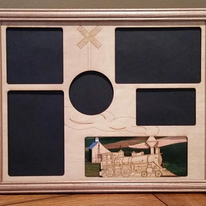 May include: A wooden picture frame with a cutout design of a train engine and a railroad crossing sign. The frame has five openings for photos, including a round opening in the center.