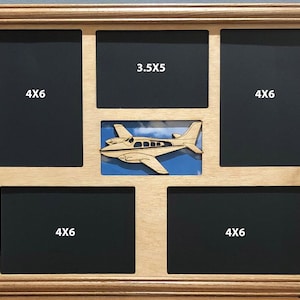 K&ouml;nnte beinhalten: Ein Bilderrahmen aus Holz mit f&uuml;nf &Ouml;ffnungen f&uuml;r Fotos. Der Rahmen hat einen Ausschnitt eines kleinen Flugzeugs in der Mitte. Die &Ouml;ffnungen sind mit den Ma&szlig;en 4x6 und 3.5x5 beschriftet.