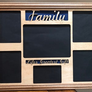 May include: A wooden picture frame with a blue background and the word "Family" cut out. The frame has six openings for pictures and the words "Life's Greatest Gift" are cut out below the top opening.