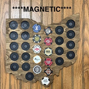 May include: Wooden Ohio-shaped magnetic display board with embedded magnets and spaces for poker chips. The board is stained a dark brown and features the word "MAGNETIC" at the top. Various poker chips with different designs are displayed.