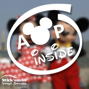 May include: White vinyl decal featuring a Mickey Mouse head silhouette with the words "A P Inside" in a circular design. The background shows Mickey and Minnie Mouse characters.