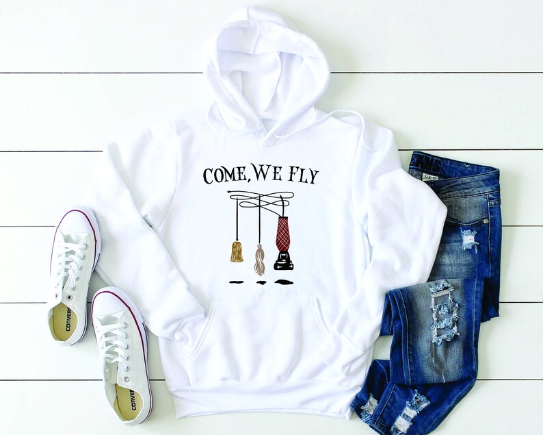 May include: White hoodie with a black graphic of three broomsticks hanging from a wire with the text "Come, We Fly".