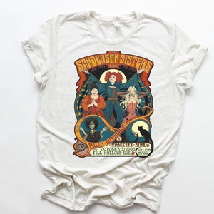 Pu&ograve; includere: Una maglietta bianca con una stampa grafica in stile vintage delle sorelle Sanderson del film Hocus Pocus. Il testo recita "The Sanderson Sisters Back From The Dead Live - Billy Butcherson - Thackery Binx - October 31, 1993 - Salem, Mass - All Hallows Eve."