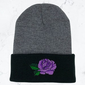 May include: Gray and black knit beanie with a purple rose embroidered on the cuff.