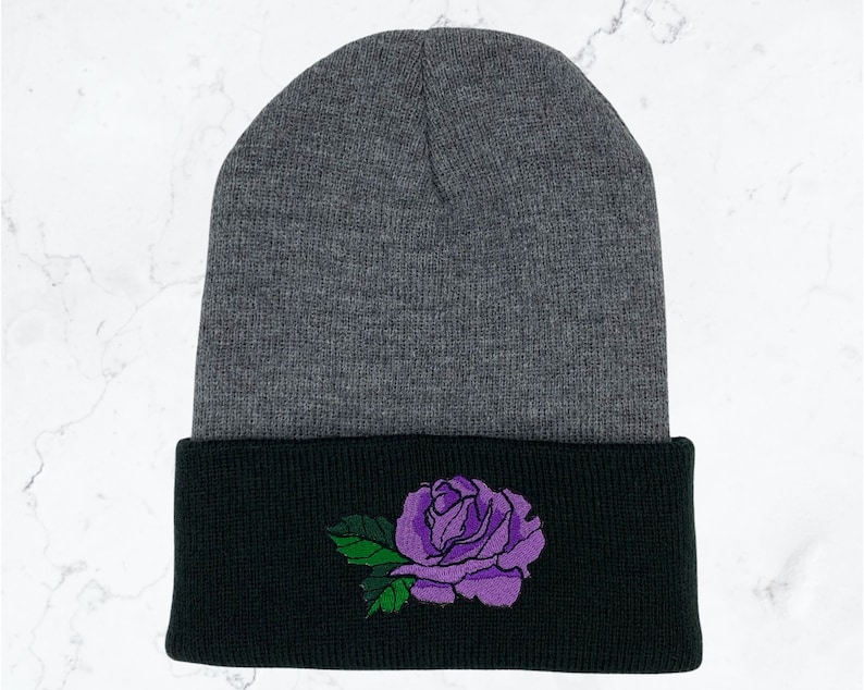 May include: Gray and black knit beanie with a purple rose embroidered on the cuff.